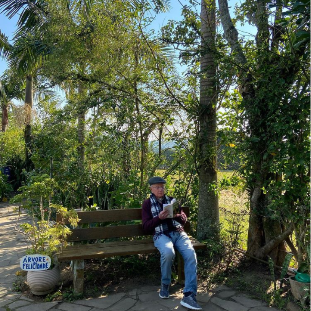 Senhor residente do Jeito de Viver EcoMorada Sênior lendo um livro no jardim