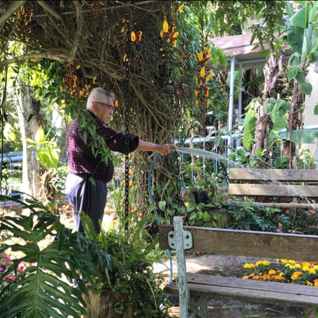 Senhor residente do Jeito de Viver EcoMorada Sênior regando as plantas do jardim